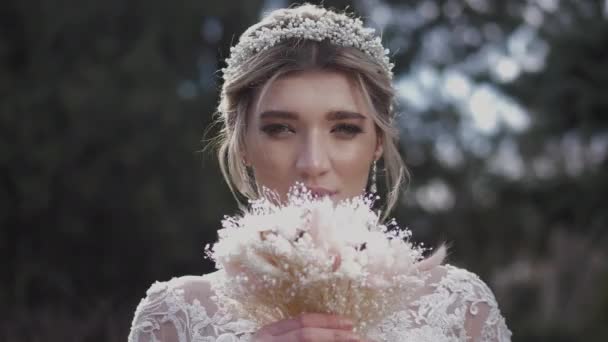Vrouw in trouwjurk houdt klein boeket in de buurt gezicht — Stockvideo