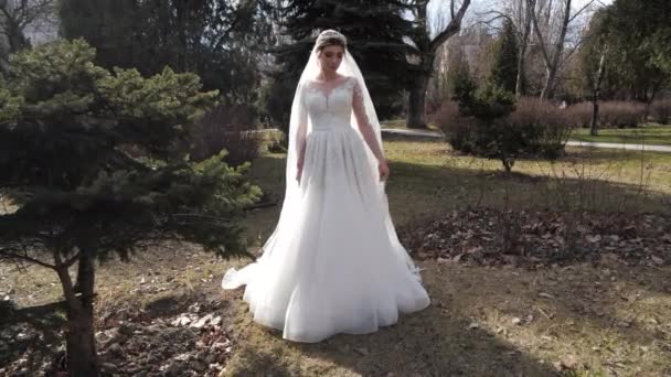 Леди в кружевном свадебном платье обертывается нежной завесой в парке — стоковое видео