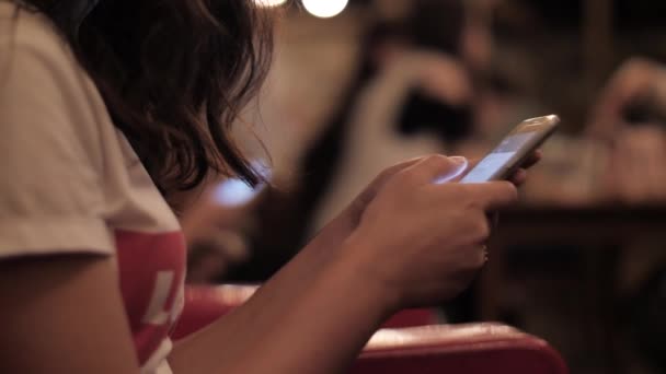 Meisje surft internet met behulp van mobiele telefoon zitten in rode fauteuil — Stockvideo