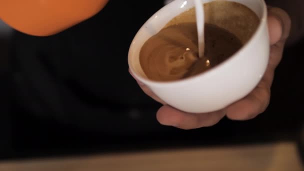 Barista wlewa mleko do filiżanki i rysuje serce na filiżance kawy — Wideo stockowe