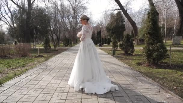 Lady in wedding dress with bouquet walks along park track — Stock Video