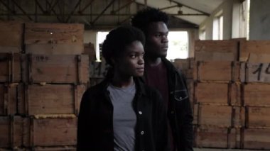 Afro-Amerikalı çift kameraya tahta kutuların yanında poz veriyor.