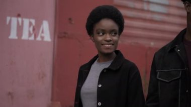 Afro-Amerikalı kadın erkek arkadaşıyla birlikte bina boyunca yürür.