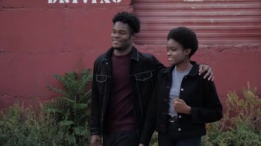 Mutlu Afro-Amerikalı çift kırmızı garajın önünden geçerken sarılıyor.