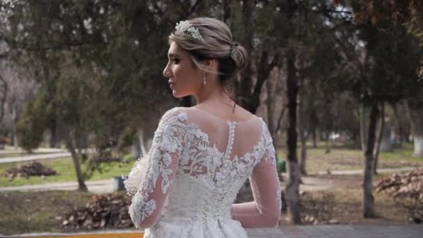 Bride in stylish wedding dress with laces and pearls in park — Stock Video