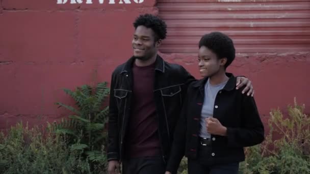 幸せなアフリカ系アメリカ人のカップルが赤いガレージを過ぎて抱擁歩く — ストック動画
