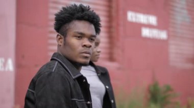 Kırmızı garajın yakınında bir kızla ceketli Afro-Amerikalı bir adam.