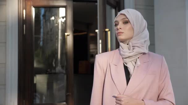 Jovem mulher no hijab fica na rua contra a porta de madeira — Vídeo de Stock