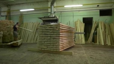 İşçi atölyede makine aracı ile cilalamak için tahta alır