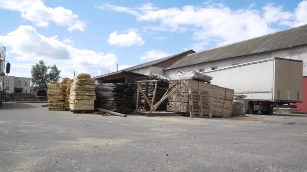 Des piles de nouvelles planches de bois se trouvent dans la cour de l'usine de travail du bois — Video