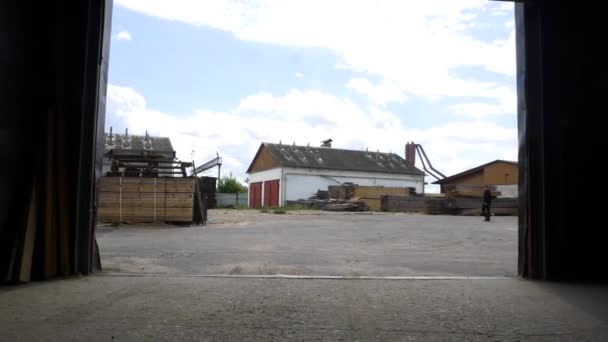 Mouvement hors de l'entrepôt pour planter la cour avec des piles de planches — Video