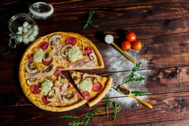 İtalyan fast food. Lezzetli sıcak pizza dilimlenmiş ve ahşap tabakta malzemelerle servis edilmiş, yakın görüş. Menü fotoğrafı.