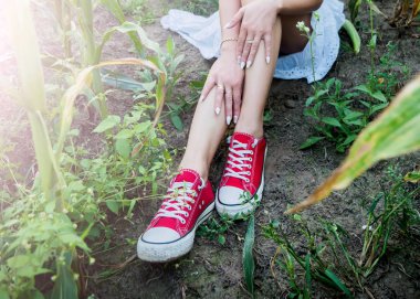 kırmızı spor ayakkabılar tarlada oturan kız