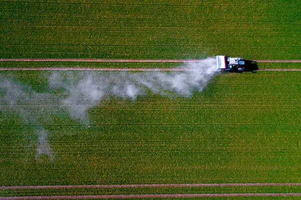 Luftbild eines Traktors, der Pestizide auf einem grünen Haferfeld versprüht, schießt von einer Drohne — Stockfoto