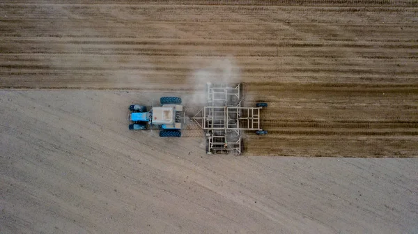 Ladang penanaman traktor pada musim semi, Tillage adalah pembuatan lahan pertanian melalui agitasi mekanis berbagai jenis pada awal musim semi pekerjaan pertanian di lahan pertanian . — Stok Foto