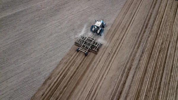 Aerial top view of a tractor, combine harvester plowing agricultural land in the spring