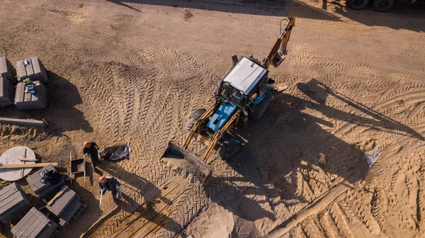 Vägtransport arbeten, reparation, om ett tjockt skikt av asfalt, betong, stora lastbilar, traktorer, vägmarkeringar, röda och gula vägskyltar, högar av sand, jord, gamla byggnader, människor gör vägen — Stockfoto