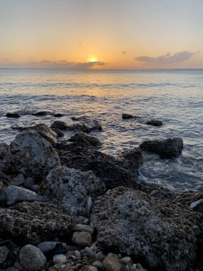 Gürcistan'da bir taş plaj ortasında denizde gündoğumu