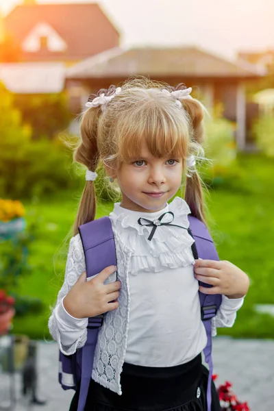 Liten jente med en ryggsekk nær skolen – stockfoto