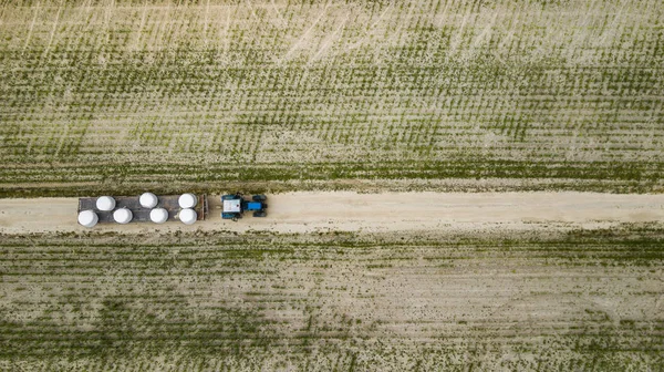 Tractor rides on the field and carries bales of hay aerial view — Stock Photo, Image