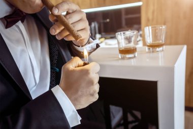 smokinli bir adam puro yakmış.