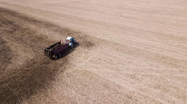 Trator no campo faz levantamento aéreo de fertilizantes orgânicos com um drone — Fotografia de Stock