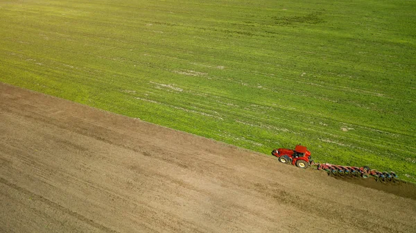 Ackerschlepper fährt mit Sämaschine über Feld und streut Mineraldünger aus — Stockfoto