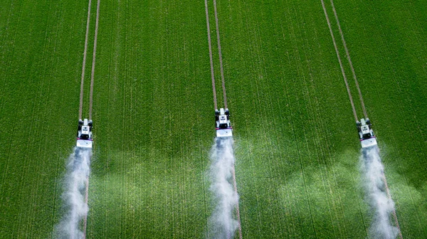 Tři traktory rozprašování pesticidů na zeleném horním pohledu — Stock fotografie