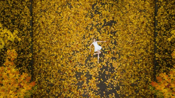 단풍나무에 누워 있는 소녀가 맨 위에서 드론으로 항공 사진을 찍고 있다 — 스톡 사진