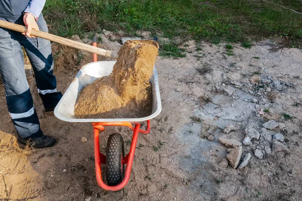 Worker pours sand into a wheelbarrow — Stock Photo, Image