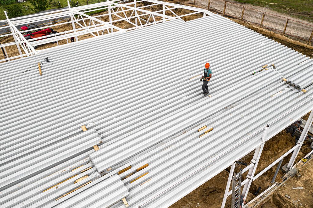 a worker on the roof mounts panels. Construction of a frame building. Top view.