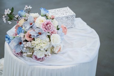 Masalar beyaz bir masa örtüsü ve güzel bir buketle kaplı.