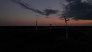 Rüzgar türbinlerinin siluetleri batan güneş manzarasına karşı