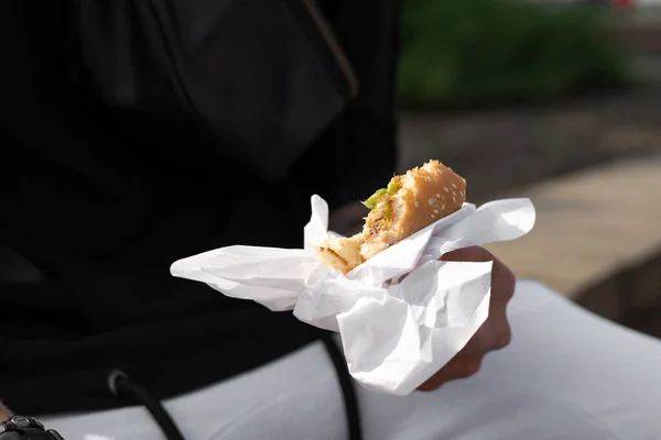 Woman is holding a bitten burger.