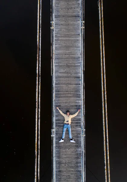水と反射した星空を背景に橋の上に男が横たわっている — ストック写真
