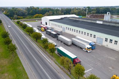 MINSK, BELARUS - Eylül 2020: Ağaç manzaralı bir fabrika. Kamyonlar yüklemek için bekliyor..