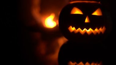 Şöminenin yanında ürkütücü Cadılar Bayramı balkabağı. Arka planda ateş.