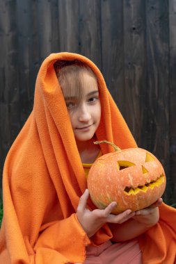 Sarı battaniyeli ve balkabaklı bir kız Cadılar Bayramı için hazırlanıyor..