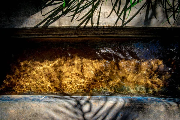 Sun reflecting in water flowing in a falaj with golden colour bo