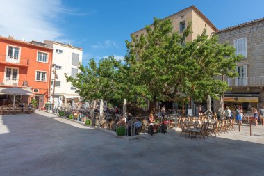 Porto-Vecchio'nun işlek ana meydanında eski bir ağaç gölgeleme masaları