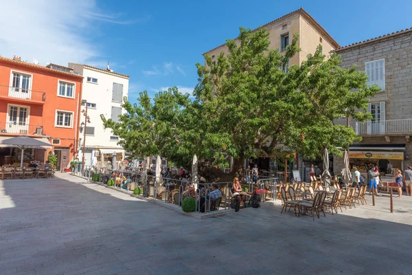 Porto-Vecchio'nun işlek ana meydanında eski bir ağaç gölgeleme masaları