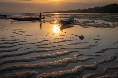 Nusa Ceningan, Bali, Endonezya - 18 Mayıs 2018: İki tekne gün batımında, tanınmayan bir kişiyle kumda mahsur kaldı