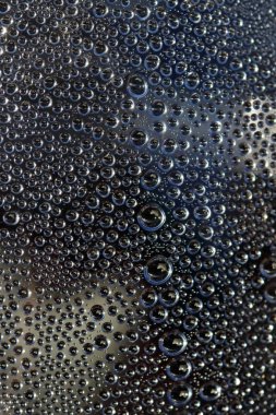 Cam karşı koyu arka plan üzerinde su damlaları