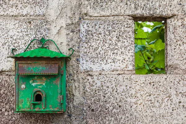 Old green mailbox on concrete wall