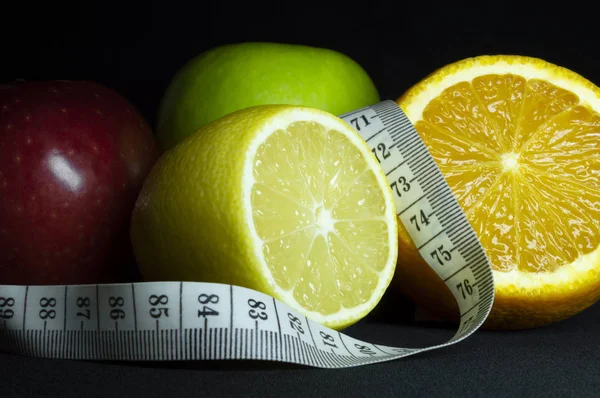 新鲜水果: 苹果, 橘子片和柠檬与测量带。黑色背景. — 图库照片