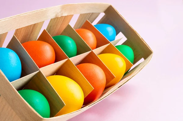 Colorful Easter eggs in a wicker basket. Pink background. Easter holiday concept. — Stock Photo, Image