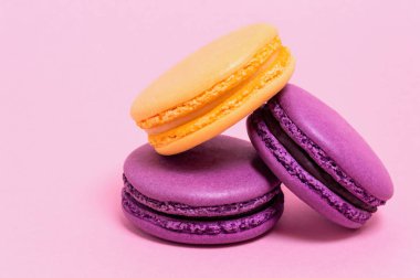 Pembe bir arka plan üzerinde üç renkli macaroons.