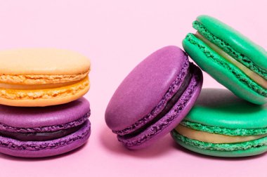 Pembe bir arka plan üzerinde beş renkli macaroons.