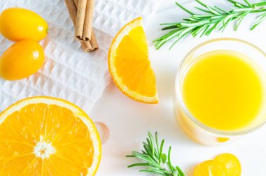 Portakal, kumquat ve biberiye ile ferahlatıcı yaz narenciye içeceği. Beyaz arka plan, düz döşeme, üst görünüm.