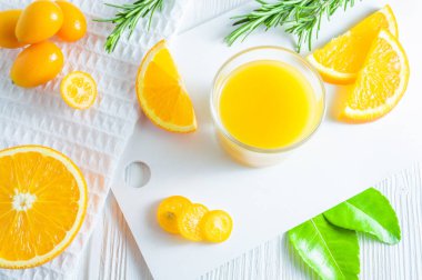 Portakal, kumquat ve biberiye ile ferahlatıcı yaz narenciye içeceği. Beyaz arka plan, düz döşeme, üst görünüm.